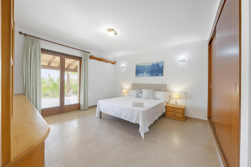 Bright and elegant double bedroom with direct access to the covered terrace and garden views.
