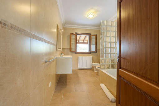 Spacious bathroom with bathtub, natural light, and stylish tiling.