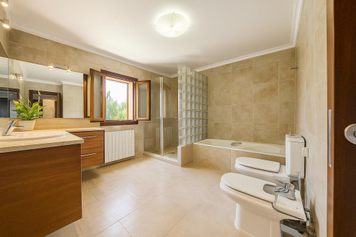 Elegant bathroom with bathtub, bidet, and natural light in Majorcan country house near Alcúdia