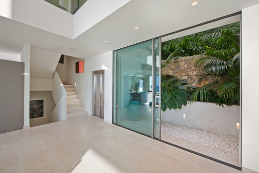 Modern entrance area with lift and lush patio