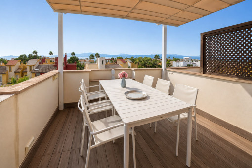 Covered rooftop terrace with table and chairs