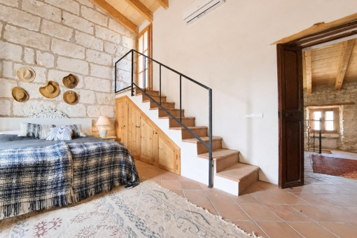 Cozy bedroom with stone wall and staircase